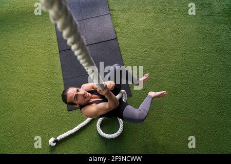 Junger Athlet Krafttraining in der Turnhalle durch Klettern am Seil mit den Händen, aktives und sportliches Lifestyle-Konzept, Texterstellung Stockfoto