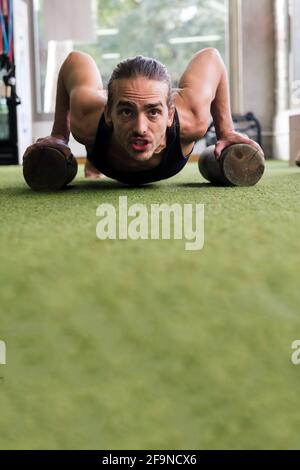 Vertikales Porträt eines Sportlers, der im Fitnessstudio Liegestütze trainiert, Sport- und Active-Lifestyle-Konzept, Texterstellung Stockfoto