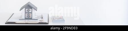 Unternehmen. Auf dem weißen Tisch befindet sich ein Hausmodell, ein Handelsdokument, Stift, Schlüssel und Geld auf dem weißen Hintergrund. Stockfoto