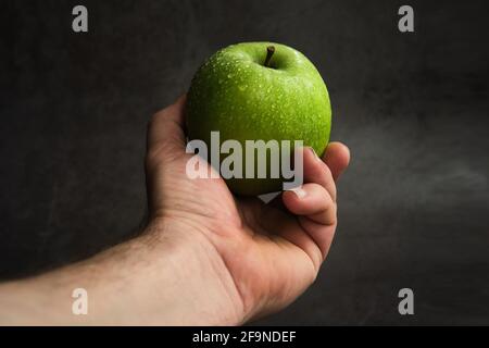 Grüner Apfel in der Hand eines Mannes Stockfoto