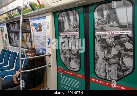 Sankt Petersburg, Russland – 15. April 2021: Junger Mann im U-Bahn-Zug mit Fotos über das 12. Weltfestival der Jugend und der Studenten in Moskau. Stockfoto