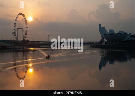 11.04.2021, Singapur, Republik Singapur, Asien - die Sonne geht während der anhaltenden Koronakrise über der Marina Bay mit dem Riesenrad Singapore Flyer auf. Stockfoto