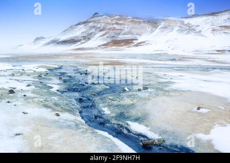 Das Hevrir-Gebiet mit kochenden Schlammtöpfen, heißen Wasserströmen und dampfenden Geysiren und bunten Felsen in Island Stockfoto