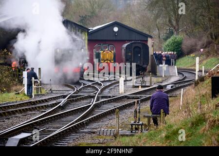 Historische Dampfeisenbahn oder Lok, die Rauchwolken aufblähen (Eisenbahner an den Punkten, Enthusiasten beobachten) - Oxenhope Station Sidings, Yorkshire England Großbritannien Stockfoto