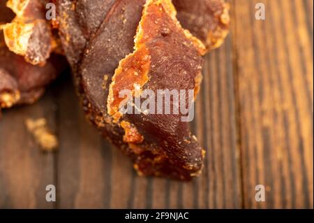 Auf einem Holztisch liegen Stücke von gesalzenem gepresstem getrocknetem Fischrogen. Traditioneller Biersnack. Nahaufnahme. Stockfoto