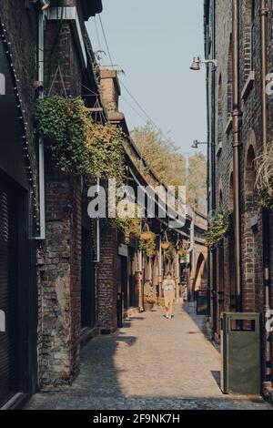 London, Großbritannien - 12,2020. August: Reihe geschlossener Torbogen-Geschäfte in Camden Market, Frau geht vorbei. Begonnen mit 16 Ständen im Jahr 1974, Camden Market ist einer von Stockfoto