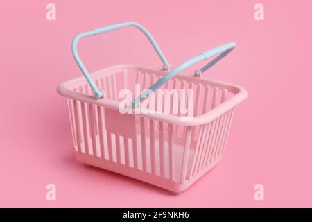 Bunte Kunststoff-Einkaufskörbe. Leerer rosafarbener und blauer Supermarkt-Korb auf rosa Pastellhintergrund. Kreatives minimalistisches Design, Online-Shopping. Blac Stockfotografie