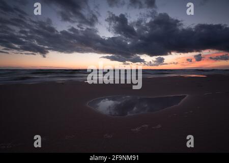 Sonnenuntergang am Strand mit den Wolken, die sich in einem spiegeln Pool mit Wasser Stockfoto