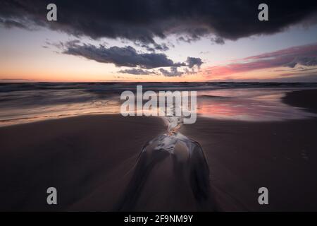 Schöner Sonnenuntergang über bredsand, einem Sandstrand, Muster nach Wellen im Sand Stockfoto