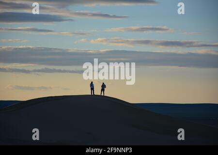 Touristen, die auf den Sanddünen in Khongoryn Els („Singing Sands“), Wüste Gobi, Mongolei, spazieren. Stockfoto