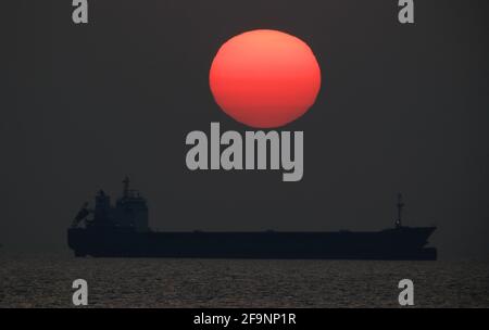 Ein Schiff sitzt am Horizont vor der Küste von Tynemouth, wenn die Sonne aufgeht. Bilddatum: Dienstag, 20. April 2021. Stockfoto