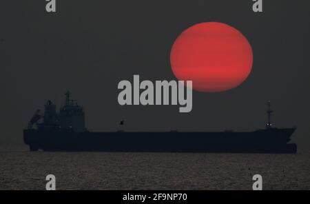 Ein Schiff sitzt am Horizont vor der Küste von Tynemouth, wenn die Sonne aufgeht. Bilddatum: Dienstag, 20. April 2021. Stockfoto