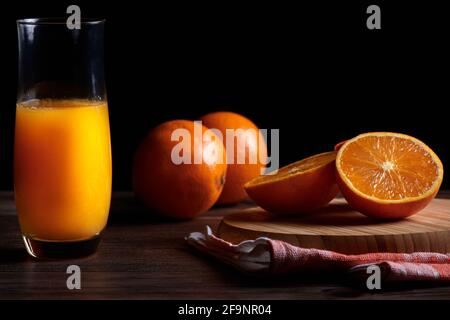 Glas frisch gepressten frischen Orangensaft mit frischen Früchten auf Holztisch. Kopieren Raum und schwarzen Hintergrund Stockfoto