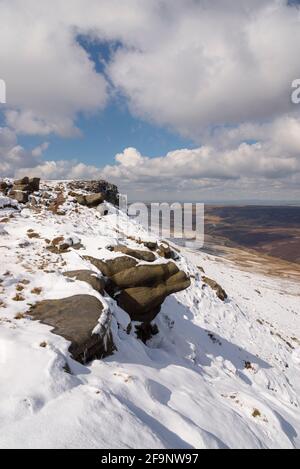 Spektakuläre Aussicht vom nördlichen Rand des Kinder Scout, Peak District mit Manchester in der Ferne. Reste von Spätschnee am Rand. Stockfoto