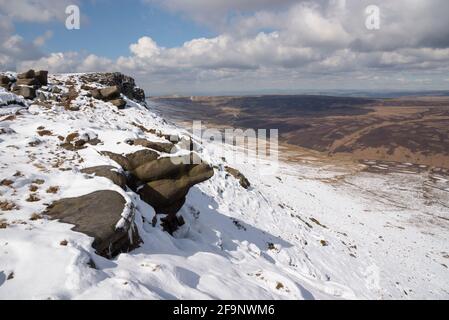 Spektakuläre Aussicht vom nördlichen Rand des Kinder Scout, Peak District mit Manchester in der Ferne. Reste von Spätschnee am Rand. Stockfoto