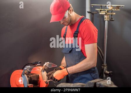 Mann in Overalls und Schutzbrille, der in der Nähe der Maschine arbeitet Stockfoto