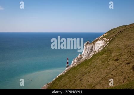 Mit Blick auf das Meer bei Beachy Head an der Sussex-Küste, mit dem Leuchtturm im Meer unter den Klippen und Kajakfahrern im Wasser Stockfoto