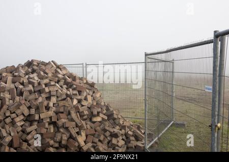 Stapel von Pflastersteinen hinter einem Zaun auf der Baustelle im Nebel, Niederlande Stockfoto