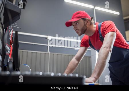 Interessierte ernsthafte Mann in Arbeitskleidung Blick auf Computer Stockfoto