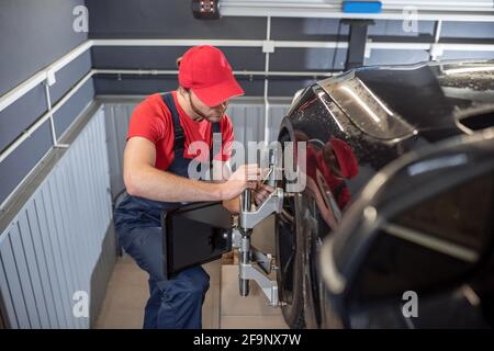 Auto Mechaniker in Overalls in der Nähe von Rad des Autos Stockfoto