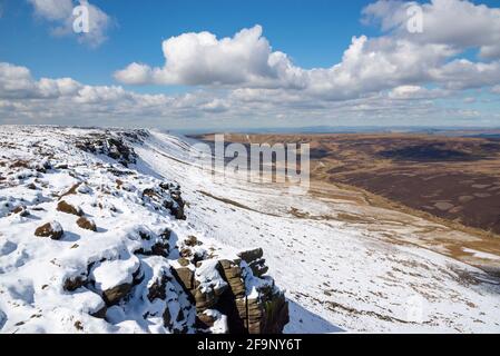 Spektakuläre Aussicht vom nördlichen Rand des Kinder Scout, Peak District mit Manchester in der Ferne. Reste von Spätschnee am Rand. Stockfoto