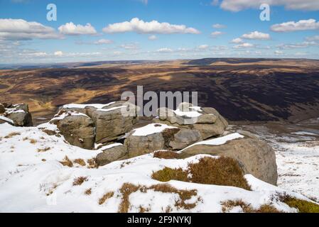 Gritstone Felsen und Schnee am nördlichen Rand von Kinder Scout im Peak District Nationalpark. Blick auf die Pennine Moors. Stockfoto