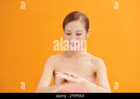 Lächelnde junge Frau trägt Creme auf ihre Hände Stockfoto