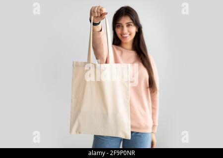 Fröhliche Frau steht mit leerer Stofftasche aus Leinwand Stockfoto