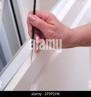 Eine ältere Frau arbeitet an der Restaurierung von Möbeln im Haus Lackierung über Späne und Kratzer Stockfoto