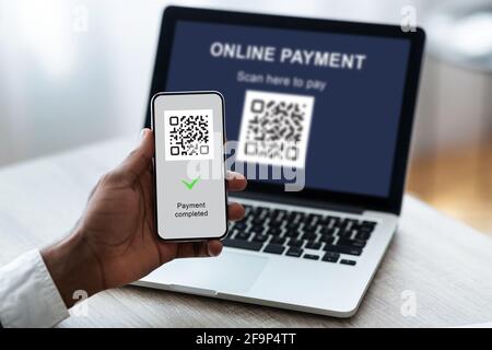 Nicht erkennbarer Geschäftsmann scannt Barcode per Smartphone vom Laptop Stockfoto