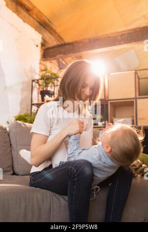 Zeit mit der Familie. Mutter und Tochter, die zu Hause Zeit zusammen haben, sehen glücklich und aufrichtig aus Stockfoto