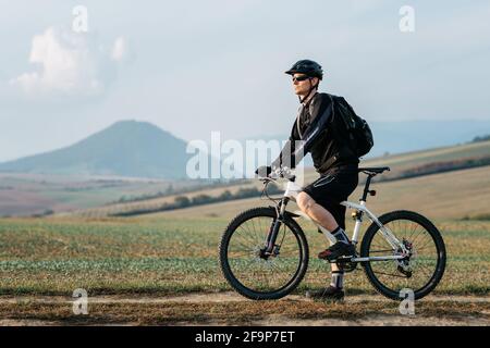 Radler, der eine Pause vom Mountainbiken einnahm. Mann, der an seinem Mountainbike steht und sich nach der Fahrt ausruht. Stockfoto