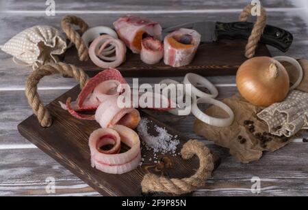 Gefrorener Fisch in Scheiben. Selektiver Fokus. Roher gefrorener Fisch auf Holzhintergrund in Holzschnitzeln geschnitten. Stroganina. Fisch mit Planken Stockfoto