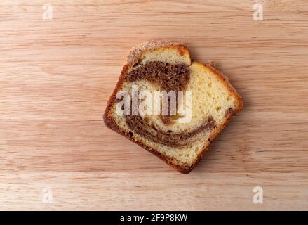 Draufsicht auf ein Stück eines frisch gebackenen Zimtmarmor-Kuchens auf einer Holzplatte. Stockfoto