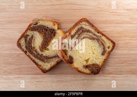 Blick von oben auf zwei Scheiben eines frisch gebackenen Zimtmarmor-Kuchens auf einem Holzhintergrund. Stockfoto