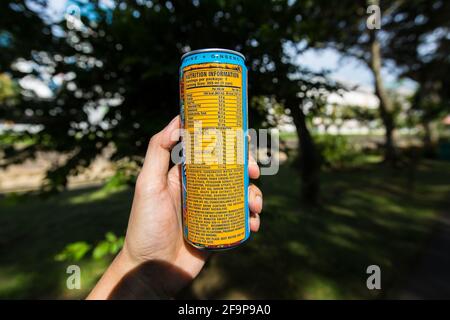 Eine Hand, die eine Monster Energy hält, kann trinken und Nährwertinformationen anzeigen. Stockfoto