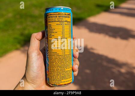 Eine Hand, die eine Monster Energy hält, kann trinken und Nährwertinformationen anzeigen. Stockfoto