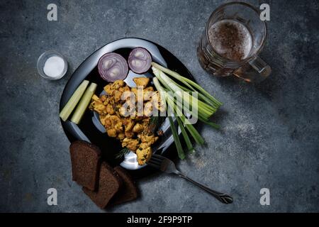 Hühnergericht, Schwarzbrot, Zwiebeln und Gurken auf dunklem Grund. Stockfoto