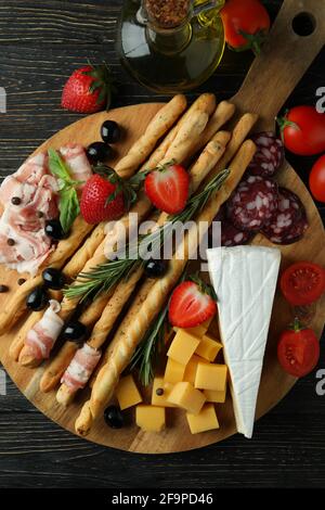 Brett mit Grissini und Snacks auf Holzhintergrund Stockfoto