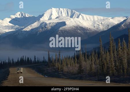 Dalton Highway - Alaska - Schnee gekrönt Berge im Hintergrund Mit einmundem LKW auf der Autobahn Stockfoto