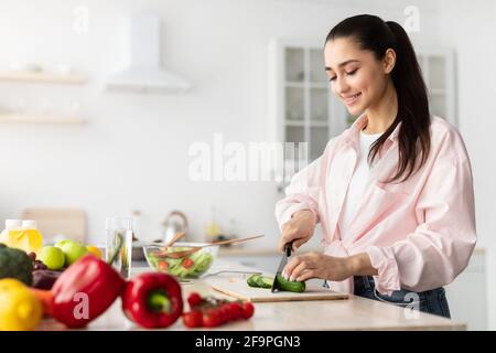 Porträt einer lächelnden jungen Frau, die frischen Salat kocht Stockfoto