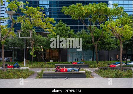 26.10.2018, Singapore, , Singapur - EINE Gruppe südasiatischer Wanderarbeiter ruht nach der Arbeit auf Bänken im Geschäfts- und Finanzviertel von Marina Bay Stockfoto