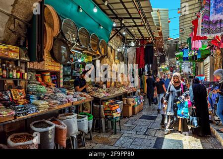 Menschen gehen auf einer schmalen Straße mit typischen Geschäften auf dem berühmten Basar in der Altstadt von Jerusalem, Israel. Stockfoto