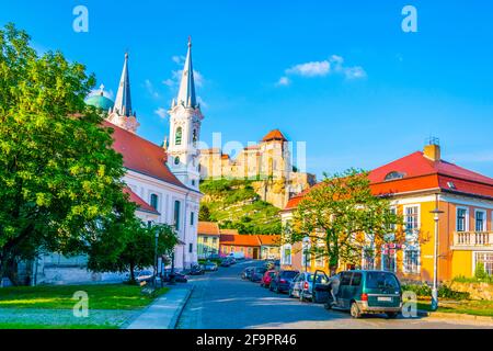 Schmale Straße in der ungarischen Stadt Esztergom mit der Kirche des heiligen Ignac und Basilika auf dem Hügel. Stockfoto