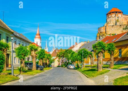 Schmale Straße in der ungarischen Stadt Esztergom mit der Kirche des heiligen Ignac und Basilika auf dem Hügel. Stockfoto