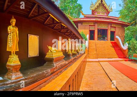 Erkunden Sie die Gasse mit vergoldeten Buddha-Bildern vor dem Ucosot des Wat Phra Kaew Temple, Chiang Rai, Thailand Stockfoto