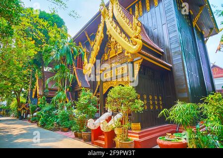 Das malerische Holzgebäude des Museums des Wat Phra Kaew Tempels, dekoriert mit goldenen Mustern, Schnitzereien und den Skulpturen von Naga Serpents, Chiang Rai, Stockfoto