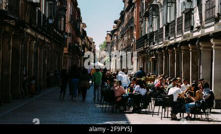 Menschen essen und trinken auf der Hauptstraße (Calle Mayor) mit neugierigen Gebäuden, Straßencafés - Alcala de Henares, Madrid, Spanien Stockfoto