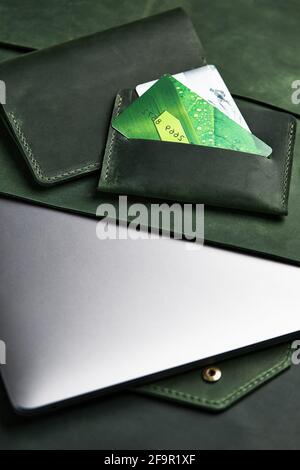 Grüne Geldbörse und Laptoptasche aus echtem Leder und Karteninhaber liegen auf dem Tisch. Draufsicht Stockfoto