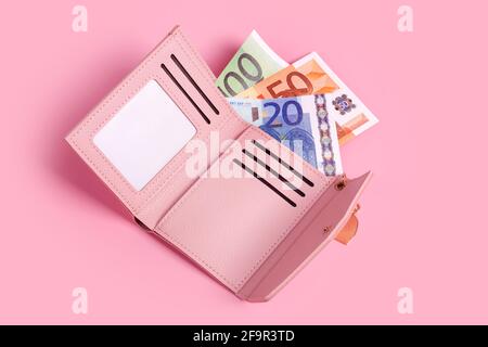 Rosa Geldbörse auf pastellrosa Hintergrund mit Euro-Scheinen darin. Nahaufnahme der geöffneten modernen Ledergeldbörse und europäischen Banknoten. Finanzen, Investitionen, Savin Stockfoto